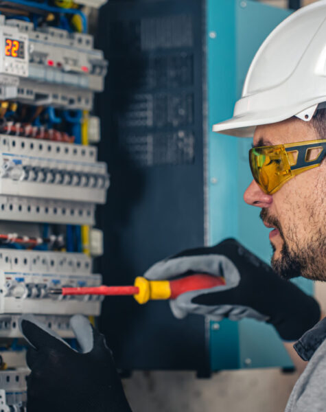 Man, an electrical technician working in a switchboard with fuses. Man, an electrical technician working in a switchboard with fuses. Installation and connection of electrical equipment.